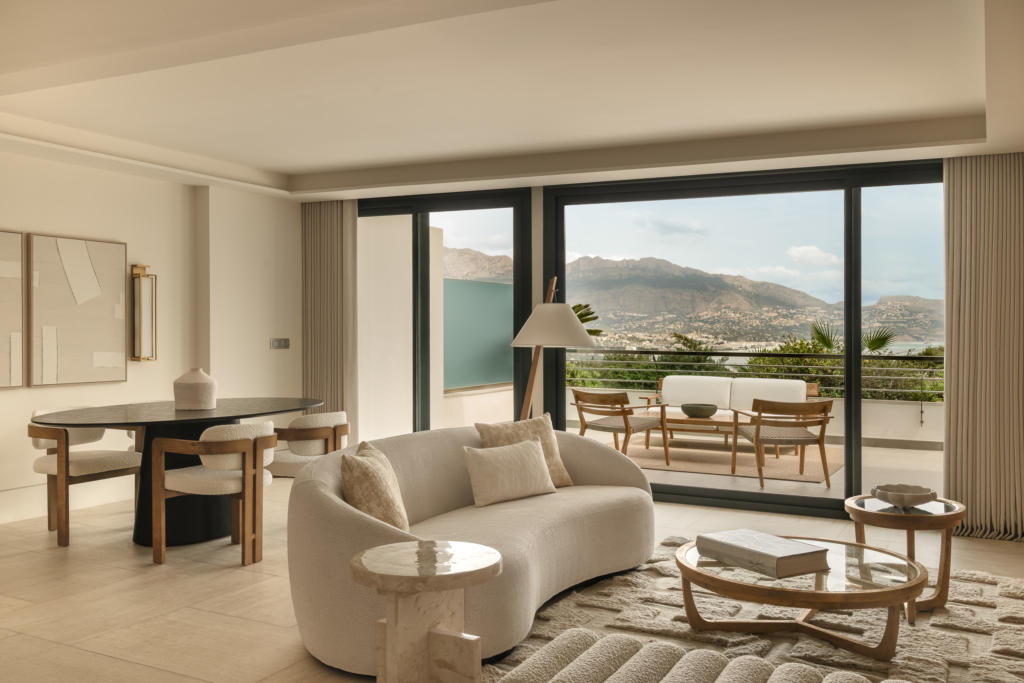 Luxury suite at SHA Spain wellness hotel, featuring a cream-toned living area, curved sofas and panoramic windows overlooking the gardens.