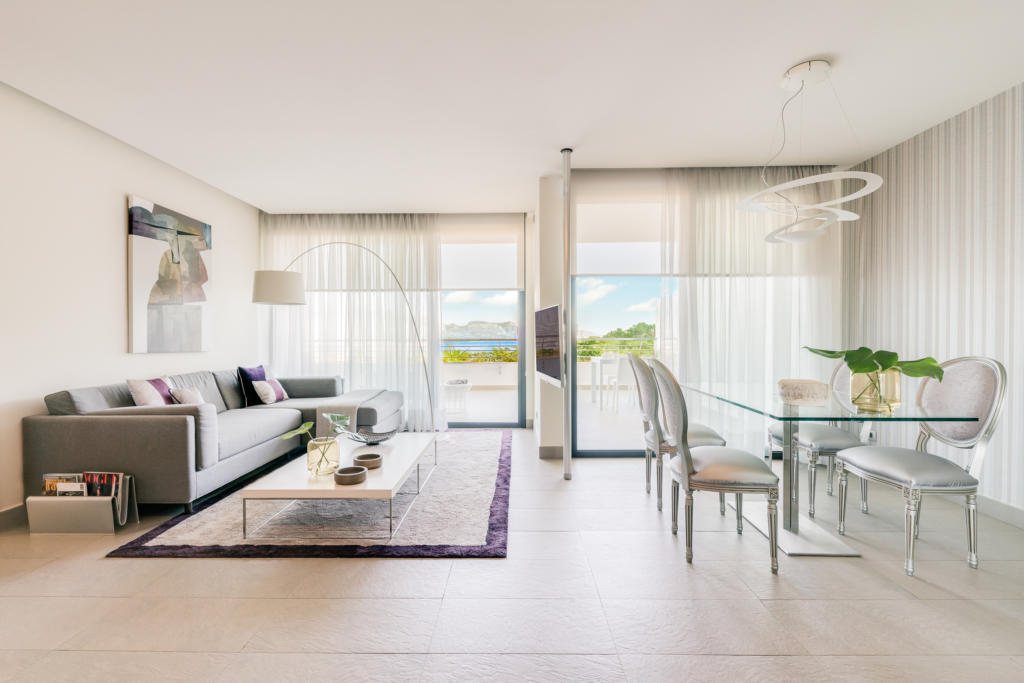 Luxury living and dining area for your health and wellness holiday at SHA Spain, featuring curtains, wooden flooring and outdoor views through large windows.